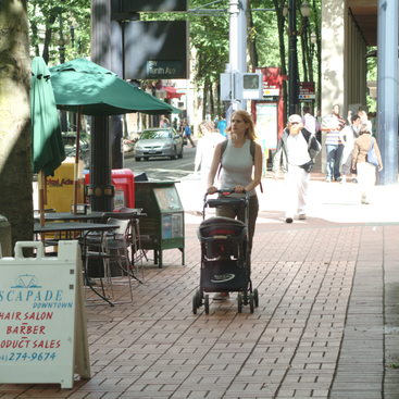 photo of a mom with stroller walking in a downtown center