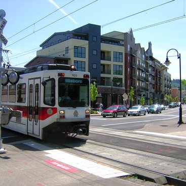 a photo of a MAX light rail train eclipsing a building in the background