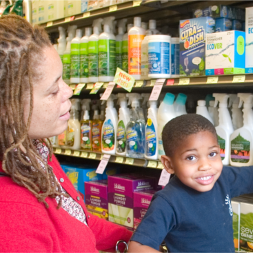 A woman and child are in the cleaning aisle in a grocery store looking at less toxic cleaners