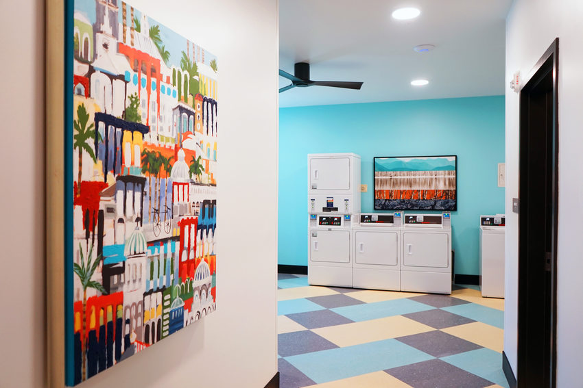 View from the doorway of a laundry room with colorful flooring and paintings.