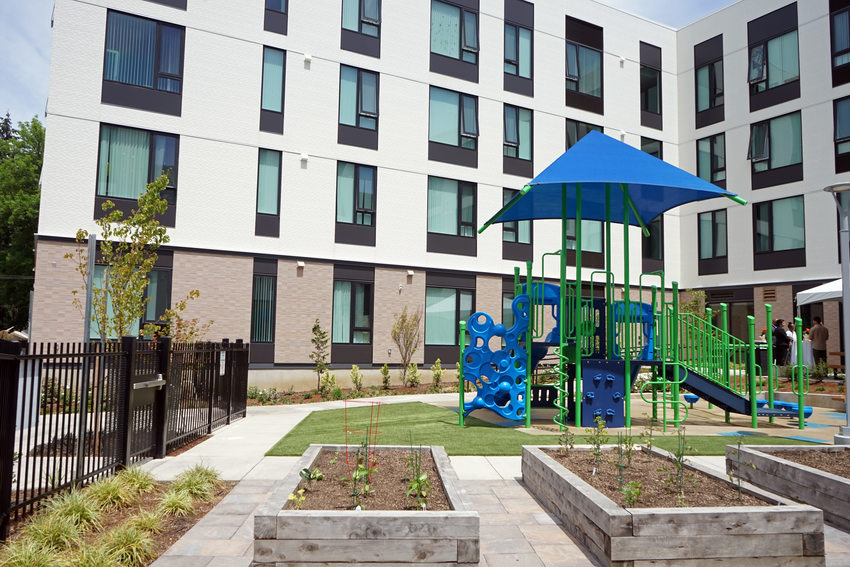 Apartment complex courtyard with play structure and raised garden beds.