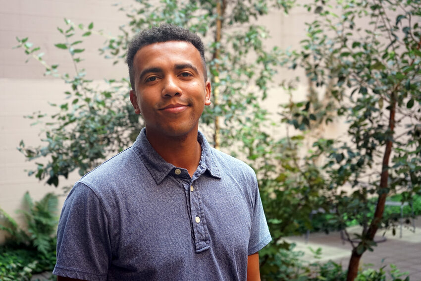 Portrait of a young man in a blue t-shirt with trees in the background