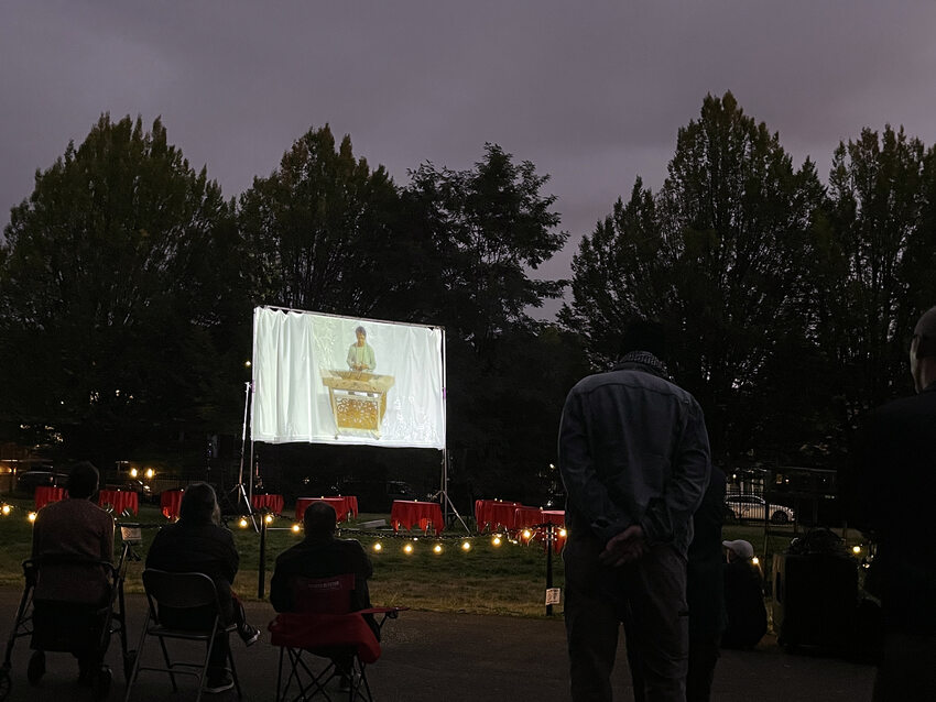 People watch a projected video of a member of the Yat Sing Music Club playing the erhu.