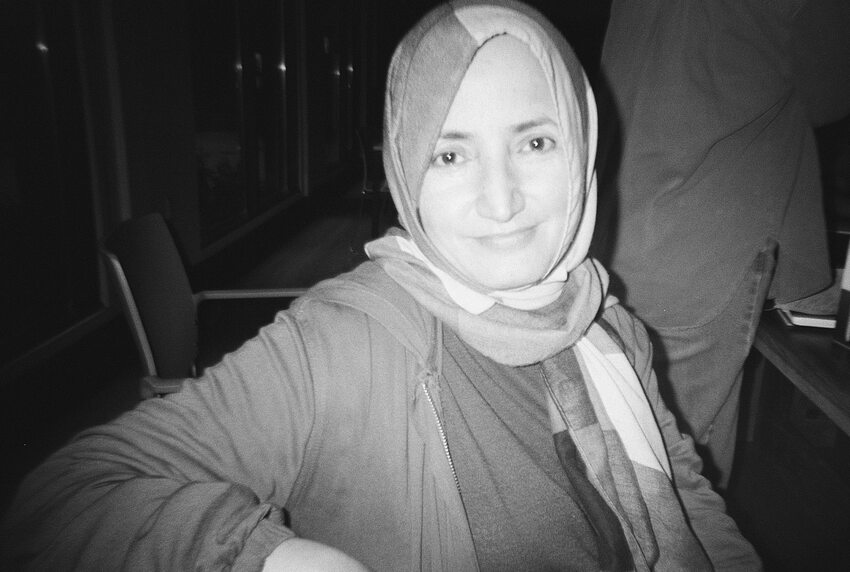 Black and white portrait of a smiling woman wearing a hijab. 