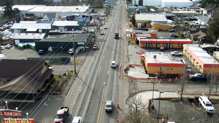 An aerial view of a four lane street with cars driving in either direction.