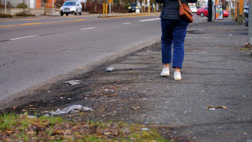 A person walks along a street without sidewalks