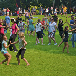 photo of men, women and children dancing in grassy area at Sunday Parkways