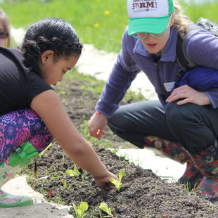 children and an instructor tend to seedlings in a garden at Sauvie Island Center