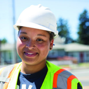 Photo of a woman wearing a hard hat and vest on a construction site