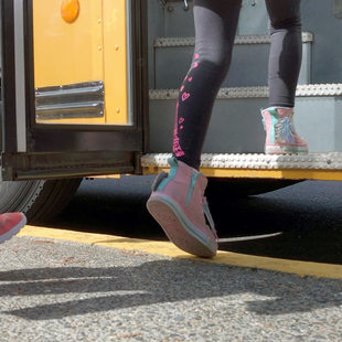 the feet of school children boarding a bus