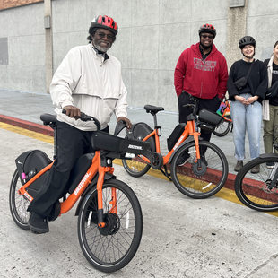 A group of adults stand with ebike