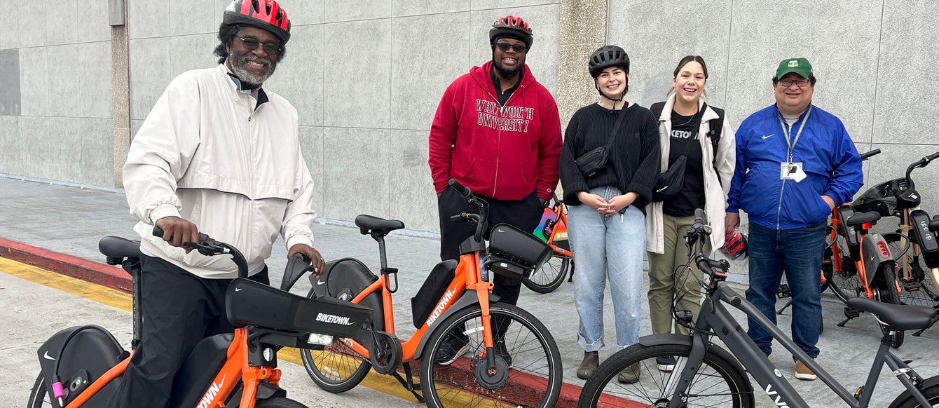A group of adults stand with ebikes