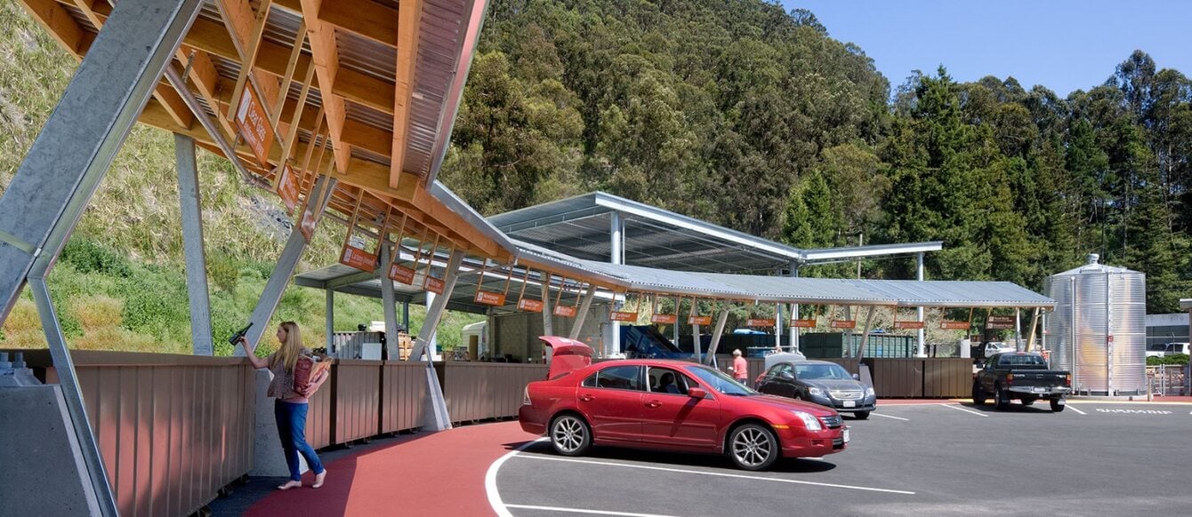 A recycling depot where a person has backed their car up to a space to drop off materials