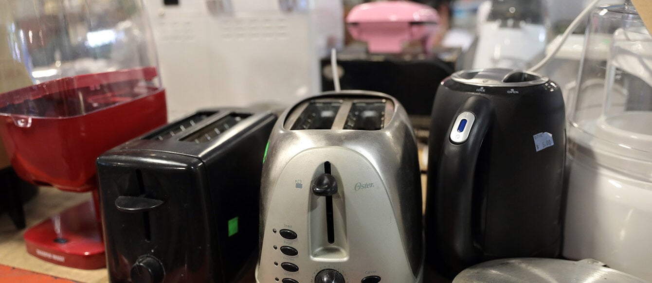 toasters and small appliances on a shelf in a reuse store