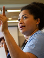 a woman raises her hand while addressing her group