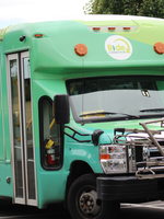 A Ride Connection shuttle bus, painted in shades of green with the Ride Connection logo prominently displayed on the front and sides of the shuttle bus.