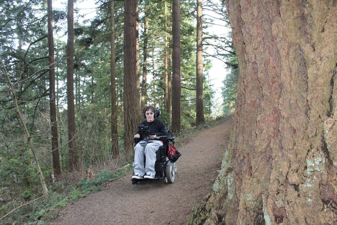 photo of Georgena Moran capturing video as she moves along a trail in her wheelchair