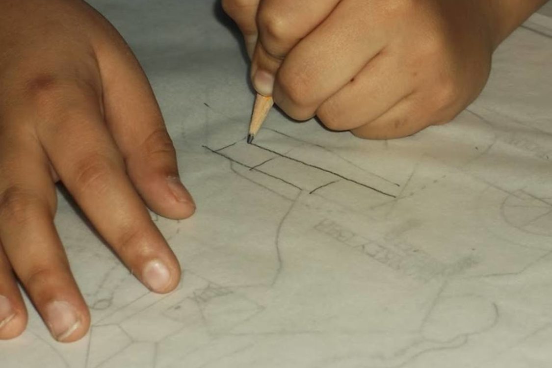 person using tracing paper and pencil to sketch designs for a park play area