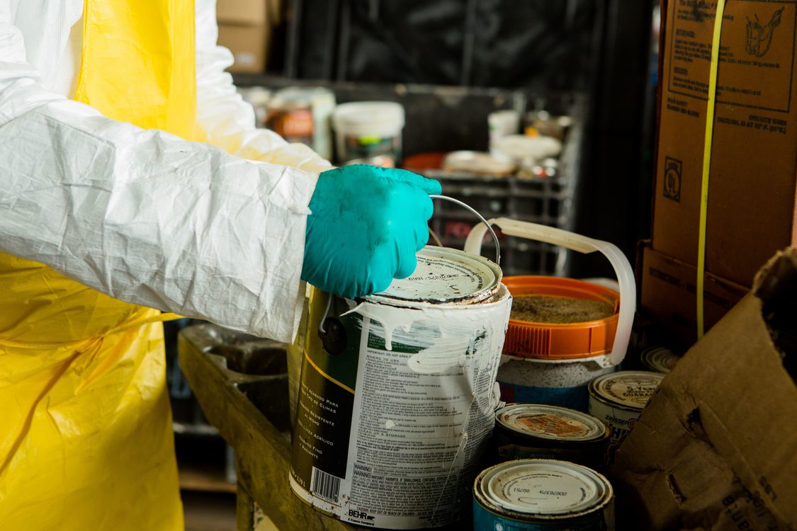 used can of paint being held by a hazardous waste technician