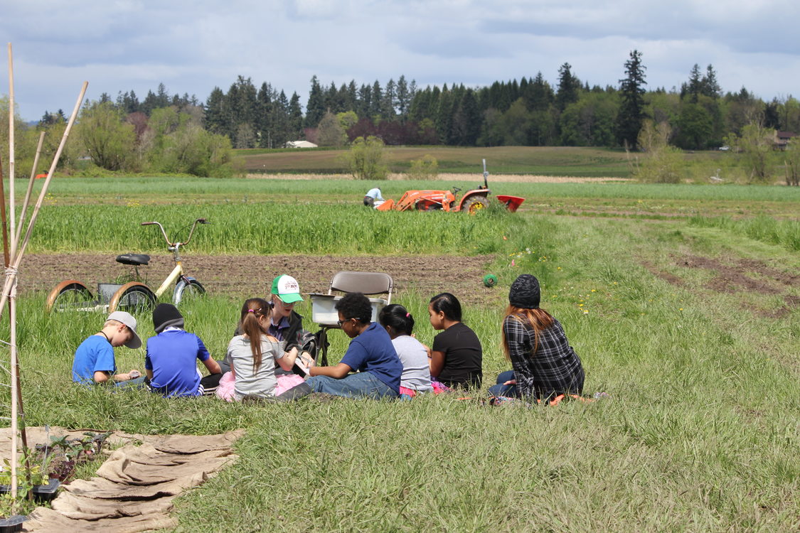 children sitting in a grassy field at Sauvie Island Center