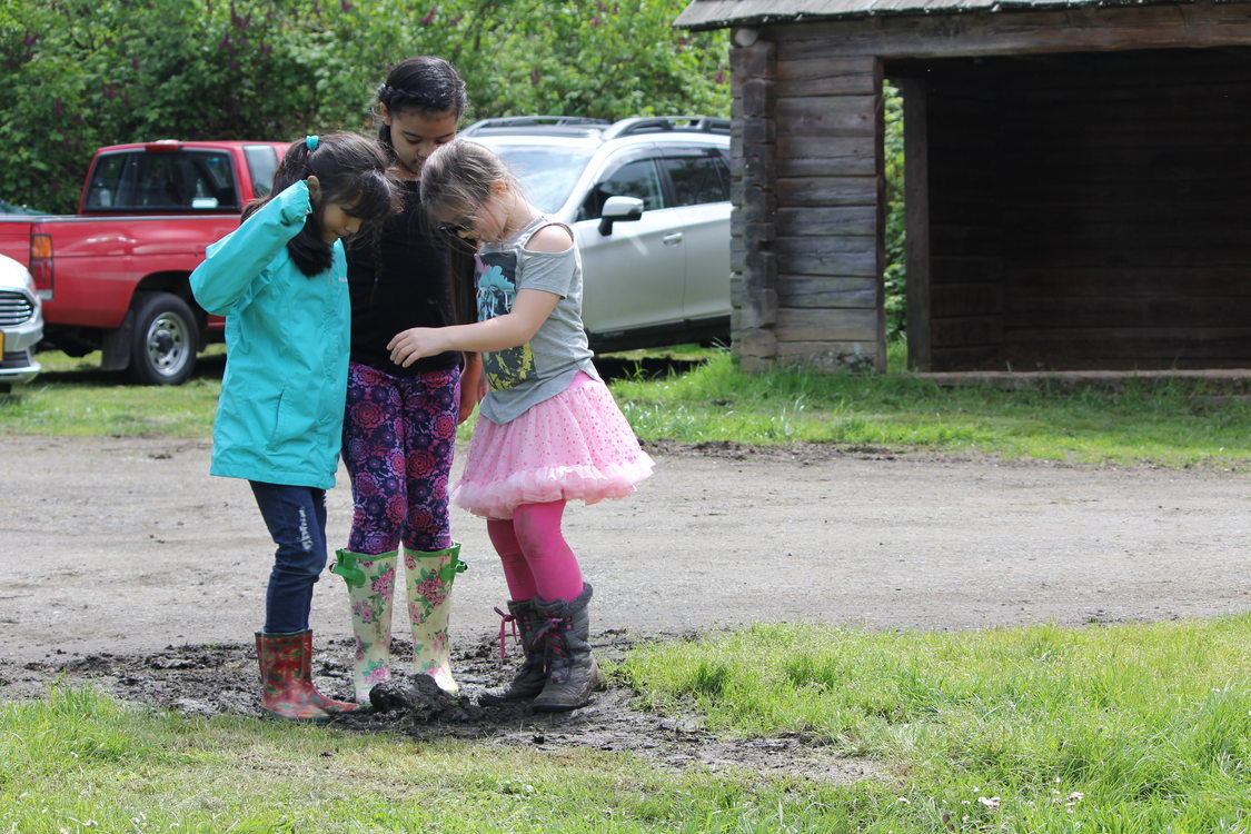 three children in boots gather together at Sauvie Island Center