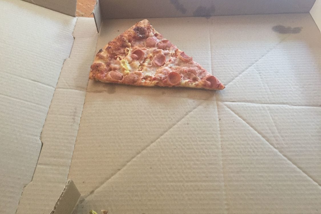A lone slice of pizza in a pizza box