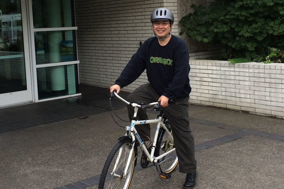Photo of Mel Huie on a bike in front of the Metro Regional Center