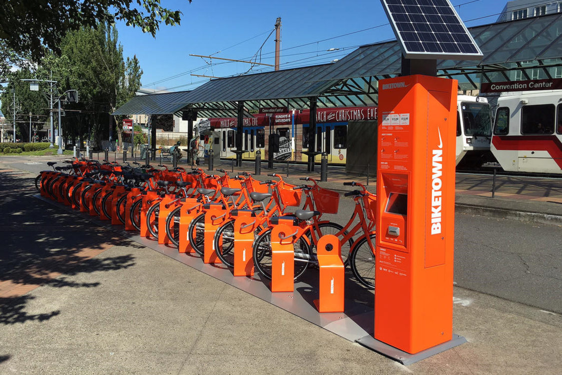 A group of Biketown bikeshare bikes next to a MAX line