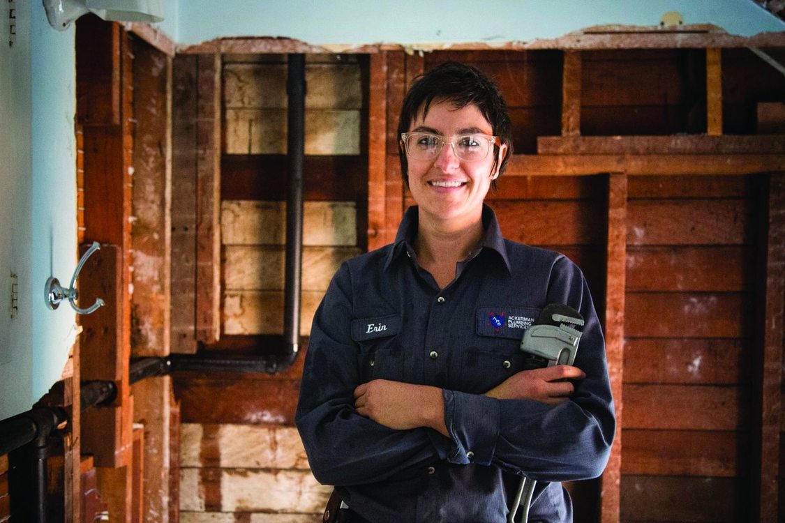 Photo of a woman in a plumbing uniform holding a tool