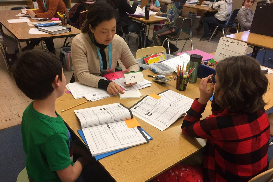 a tutor helps two grade school students with reading
