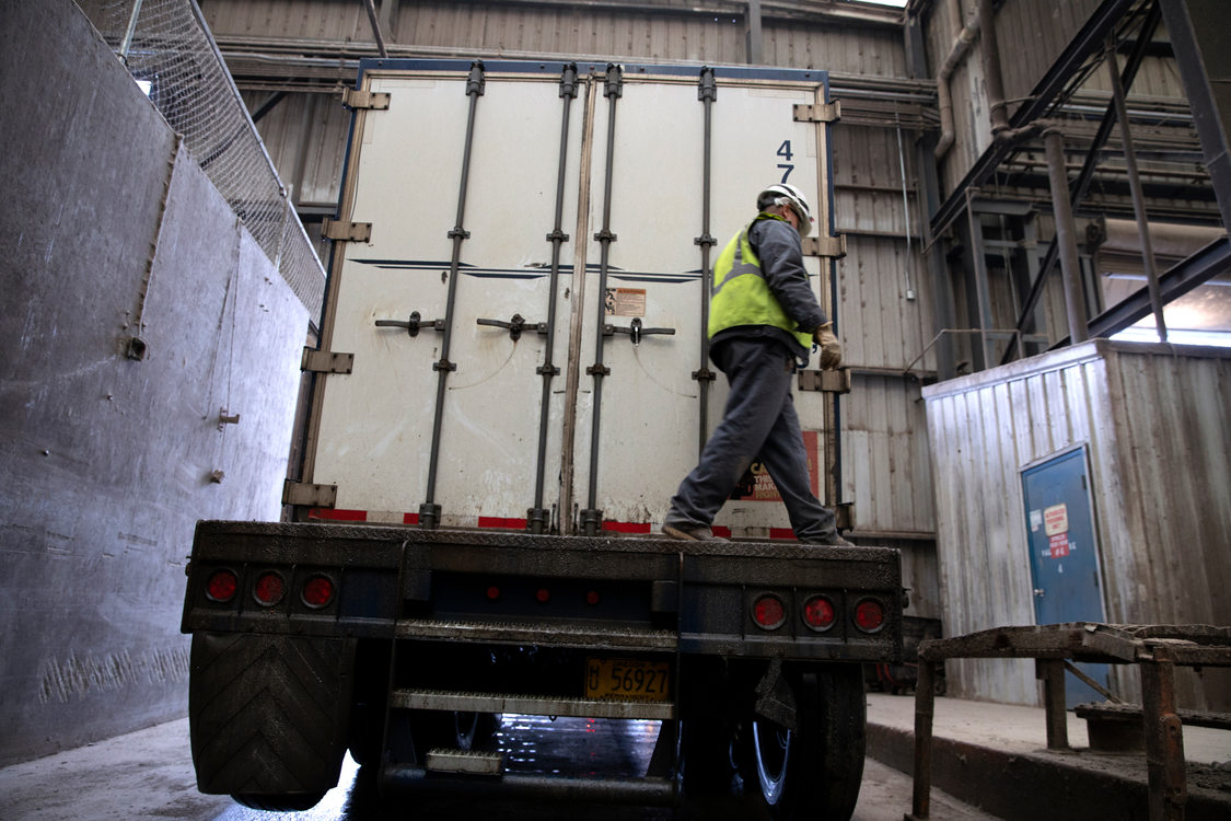 A man in a hard hat closes the back of a truck trailer