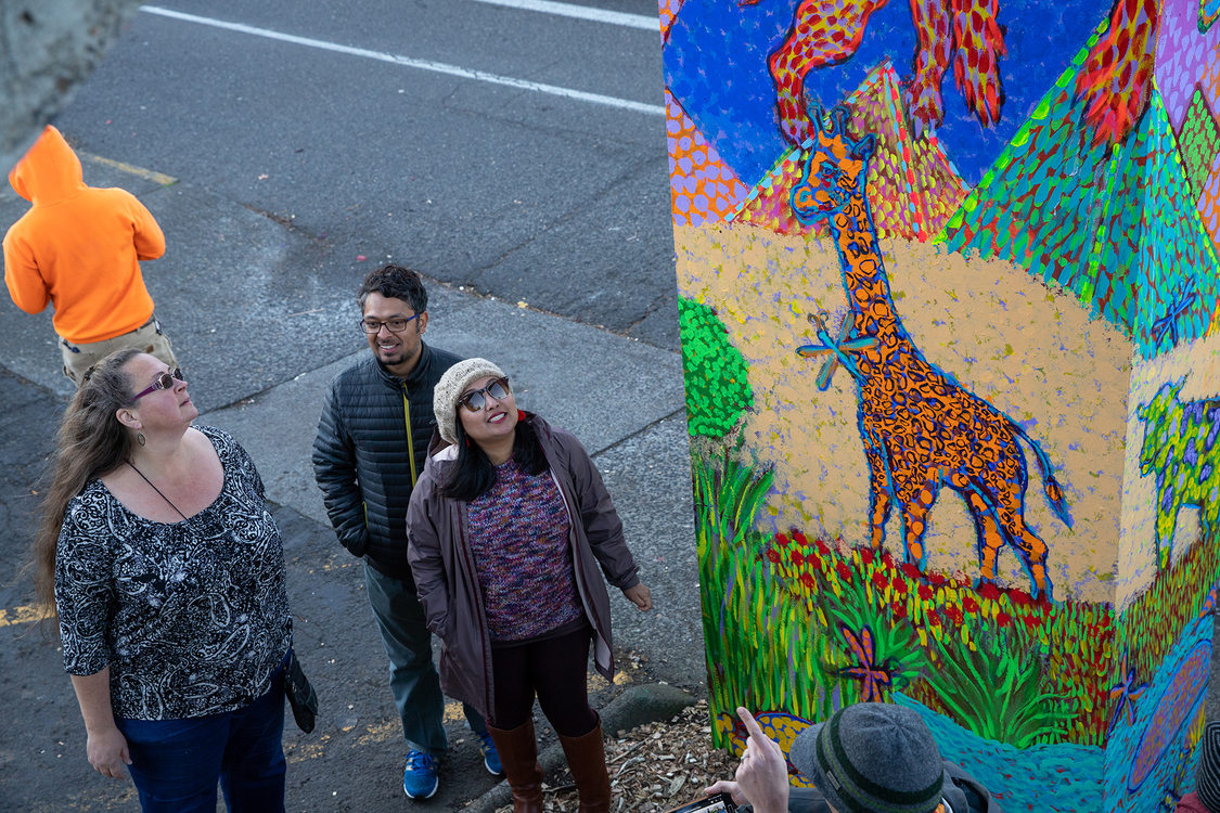 three people get up close to look at the mural paintings