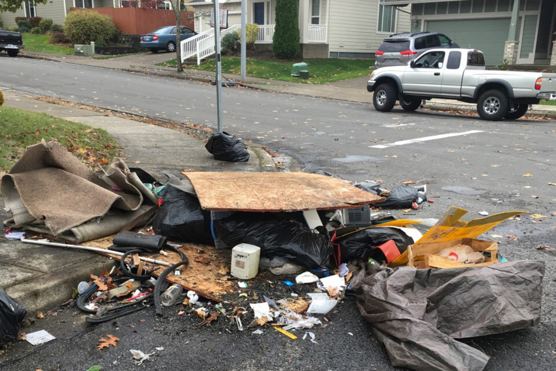 Trash and wood debris are strewn across a city corner