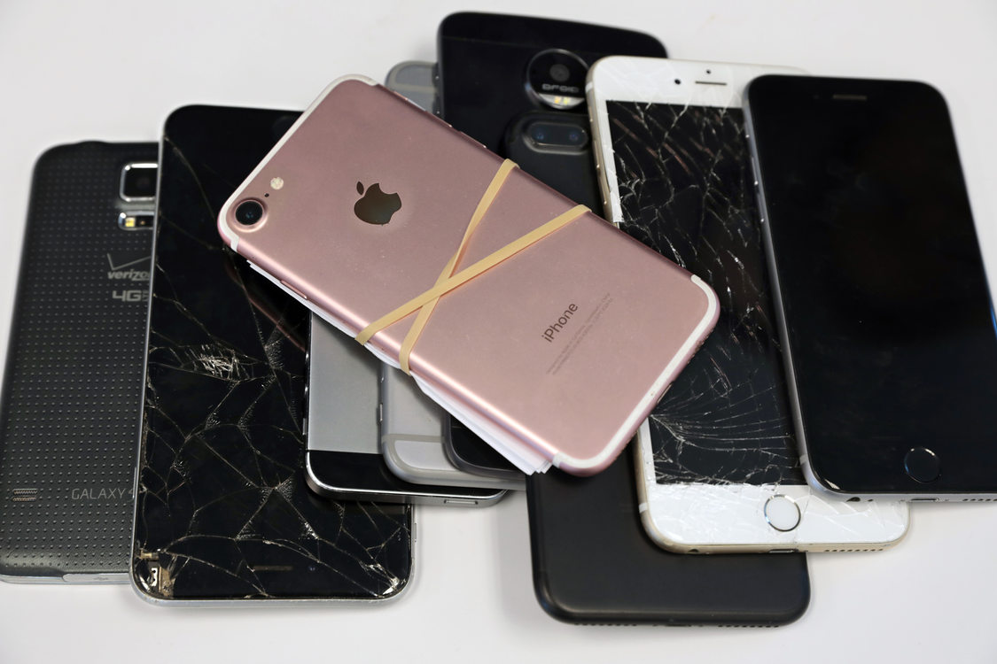 a pile of used and broken smart phones 