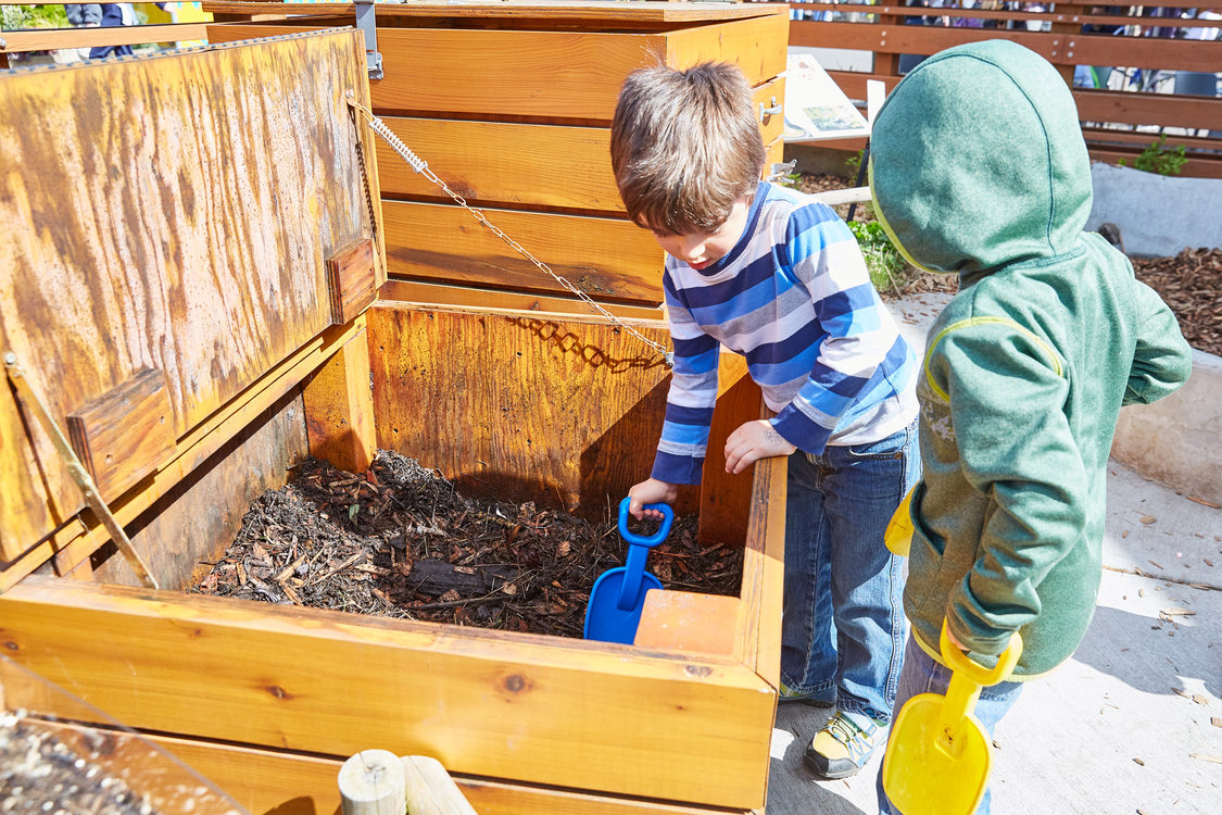 2 children digging in compost bin at zoo wildlife garden