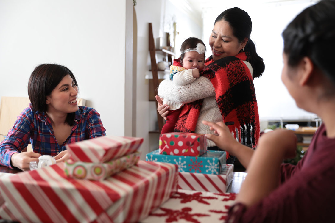 A multi-generational family gathers around holiday gifts