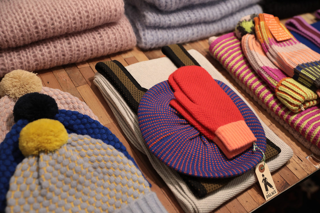 a selection of colorful  knit hats and mittens at a local shop