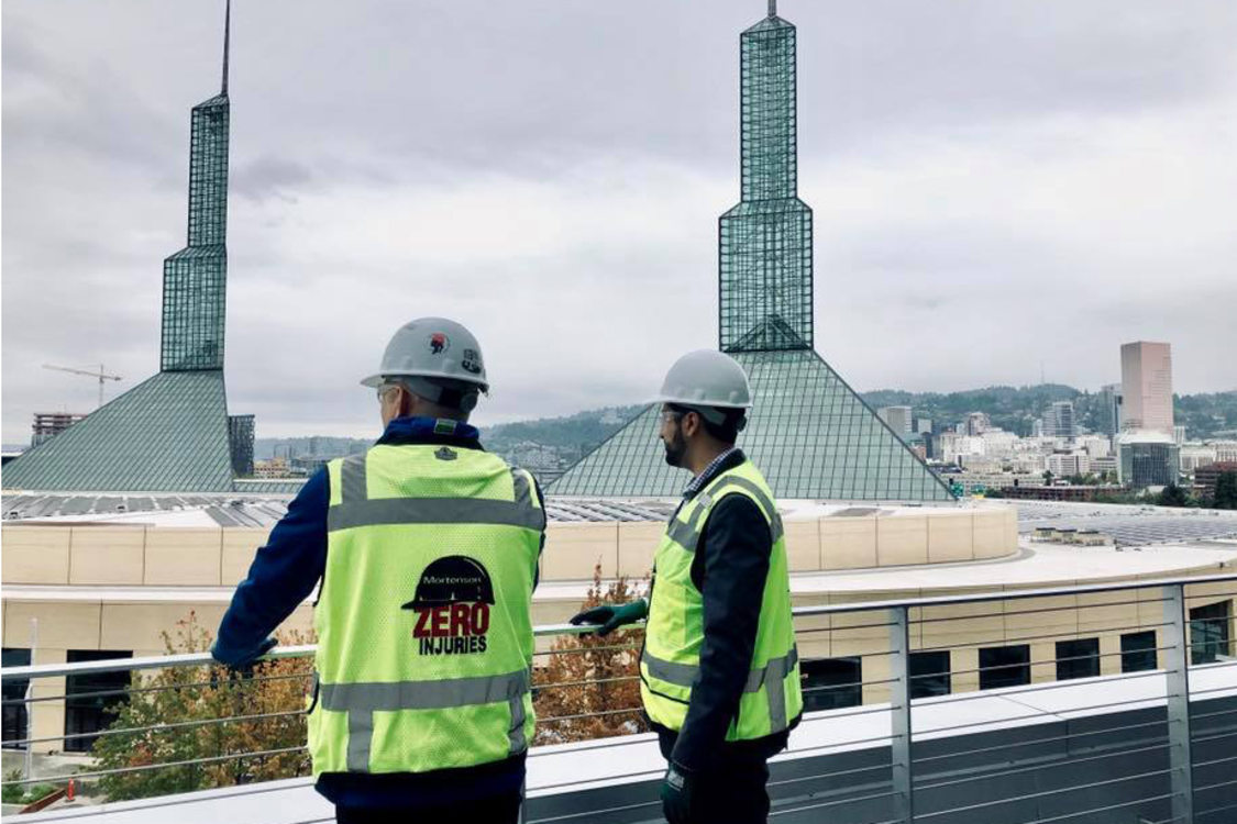 Metro Councilor Juan Carlos Gonzalez in a hard hat and construction vest overlooking the Oregon Convention Center from the top of the Hyatt Regency hotel
