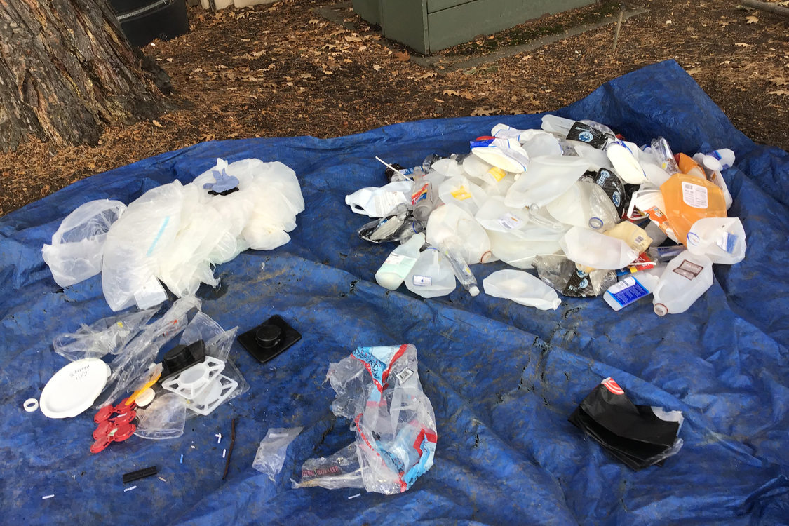 several piles of types of plastic laid out on a tarp for sorting and recycling