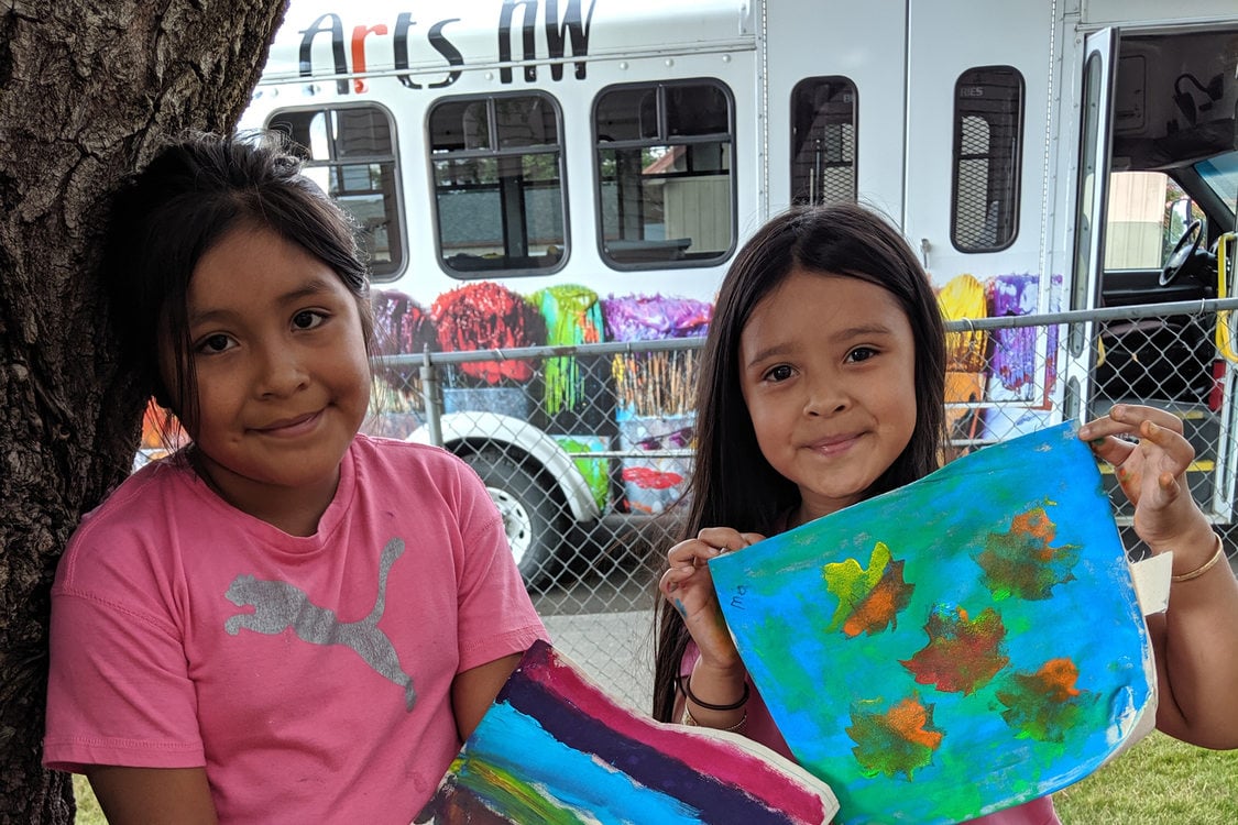 two young girls holding painted artwork they created in the Mobile Community Mural program from PlayEast