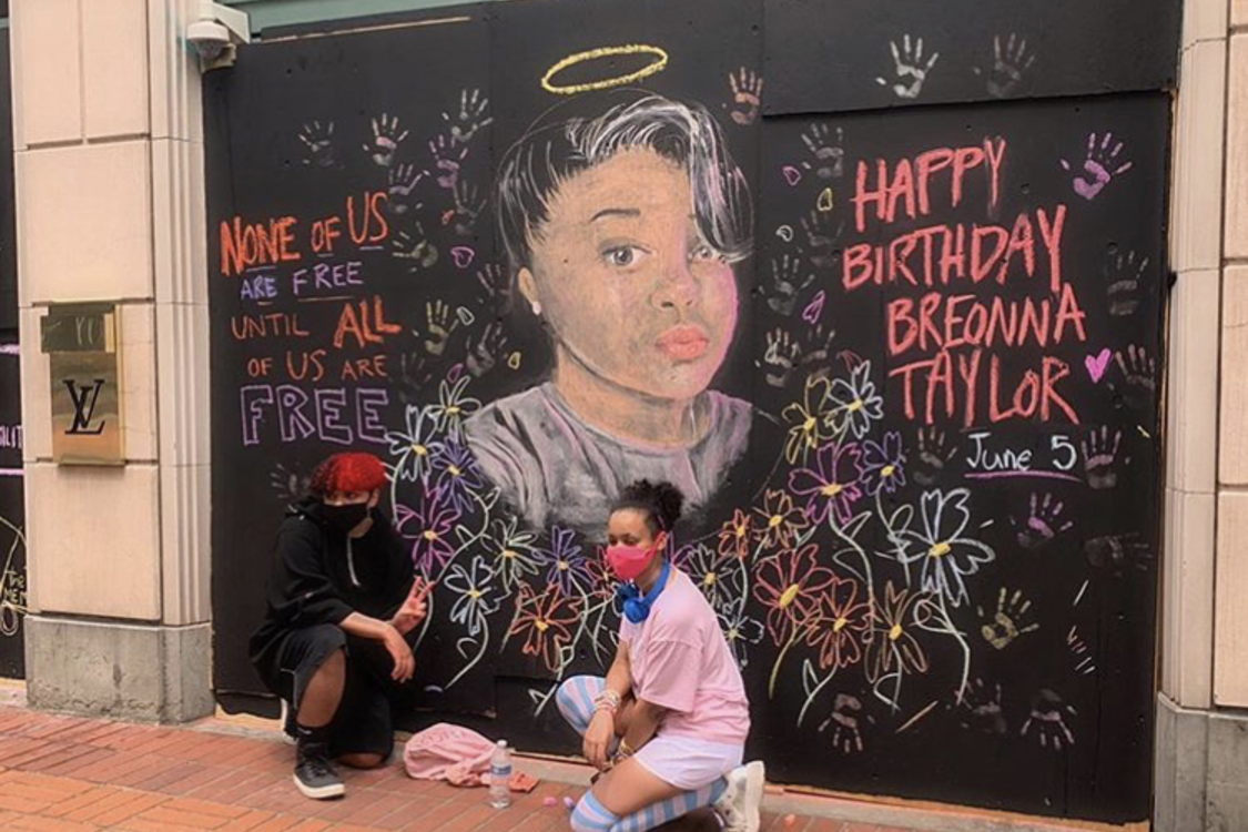two teenagers pose in front of the mural they painted of Breonna Taylor