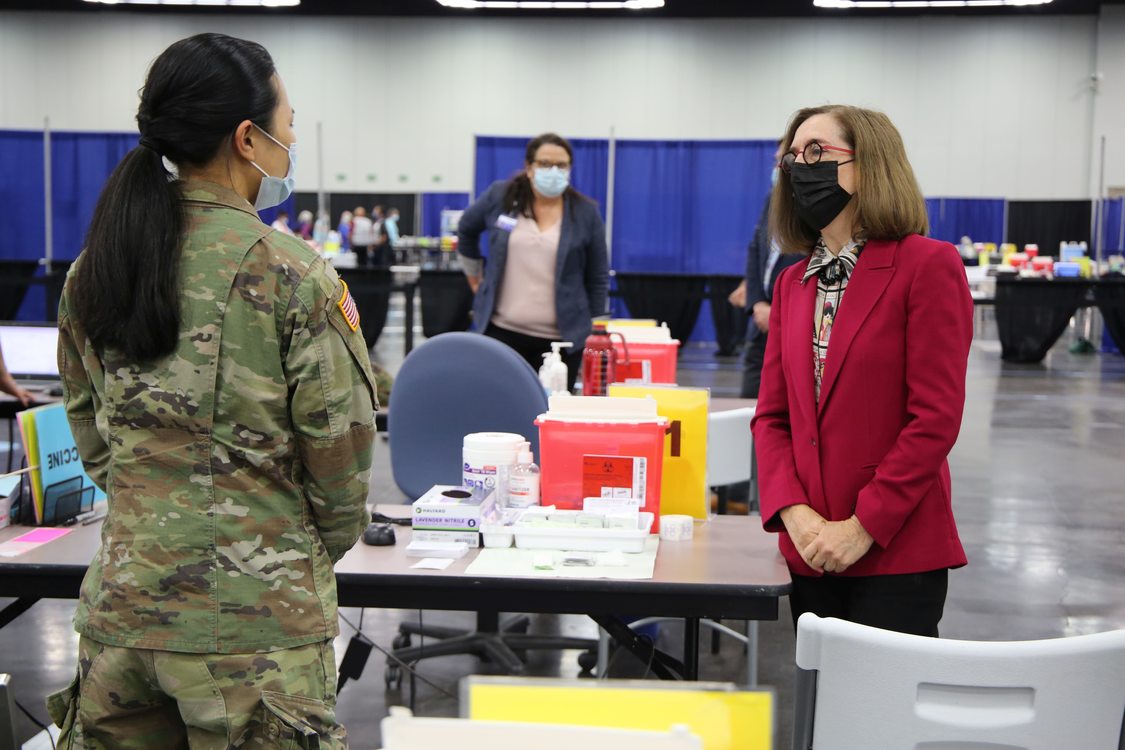 Governor Kate Brown and another woman from the National Guard wear masks at the Oregon Convention Center mass COVID-19 vaccination site