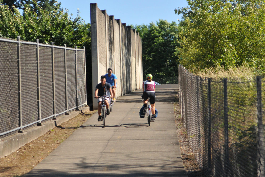 Cyclists ride their bikes along a dedicated paved trail in Portland