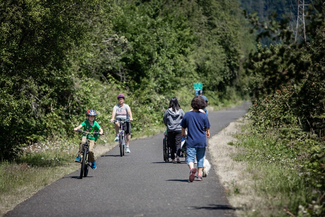 The Springwater Corridor mixed-used paved trail with cyclists, pedestrians, and people using wheelchairs sharing the paved path in greater Portland