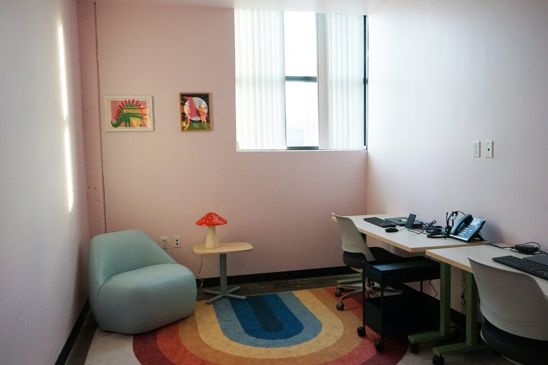 Office with small stuffed blue chair, mushroom lamp and rainbow rug