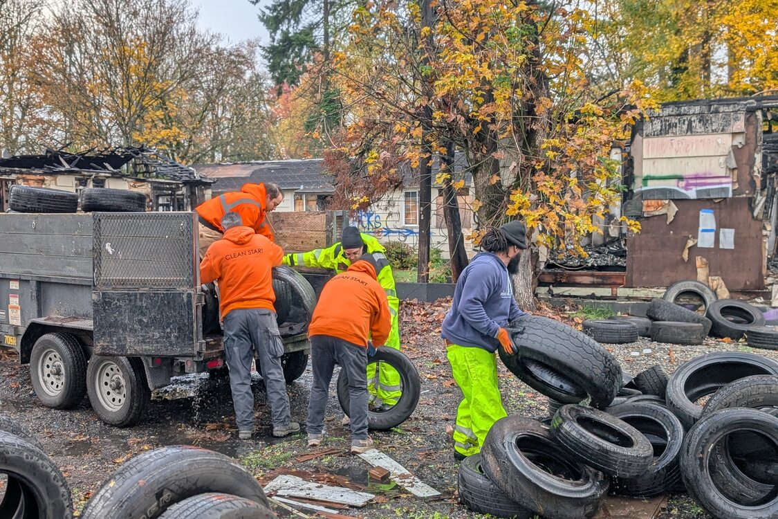 RID staff in high-visibility clothes work to load tires into the back of a work truck on a fall day. 