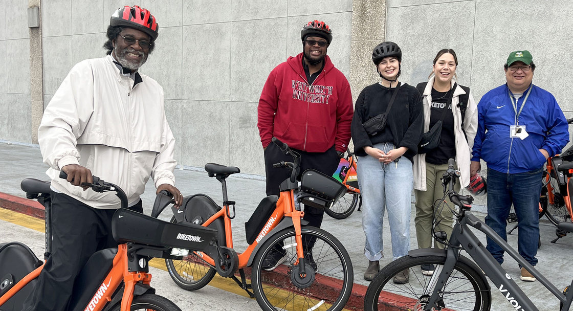 A group of adults stand with ebikes