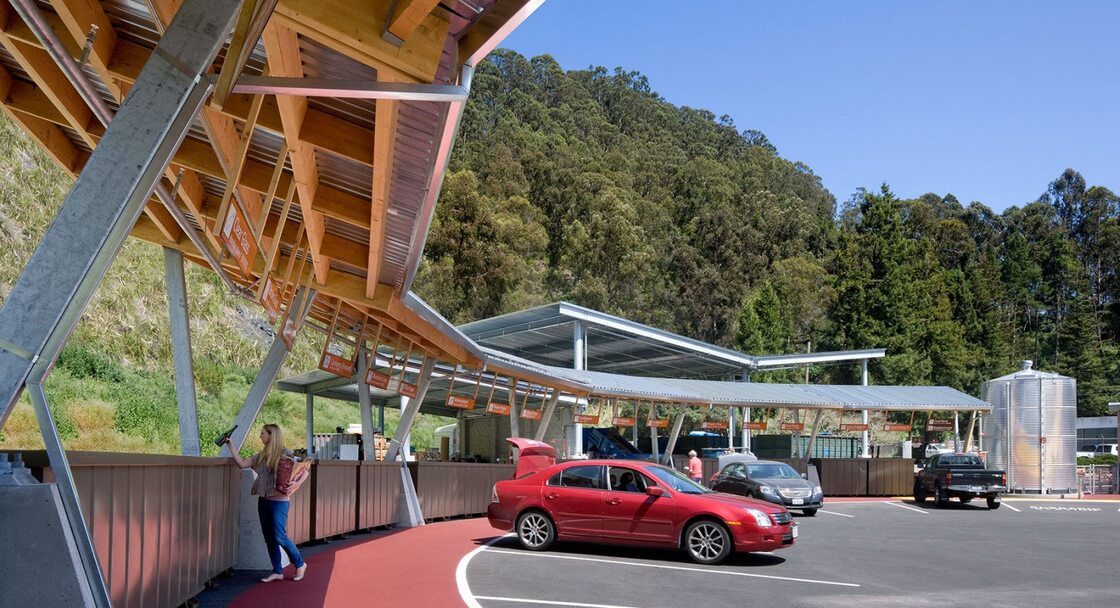 A recycling depot where a person has backed their car up to a space to drop off materials