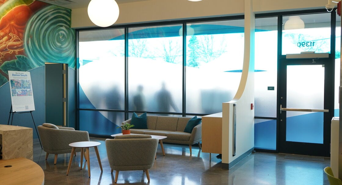 Lobby with frosted gladd windows, murals and stuffed chairs.